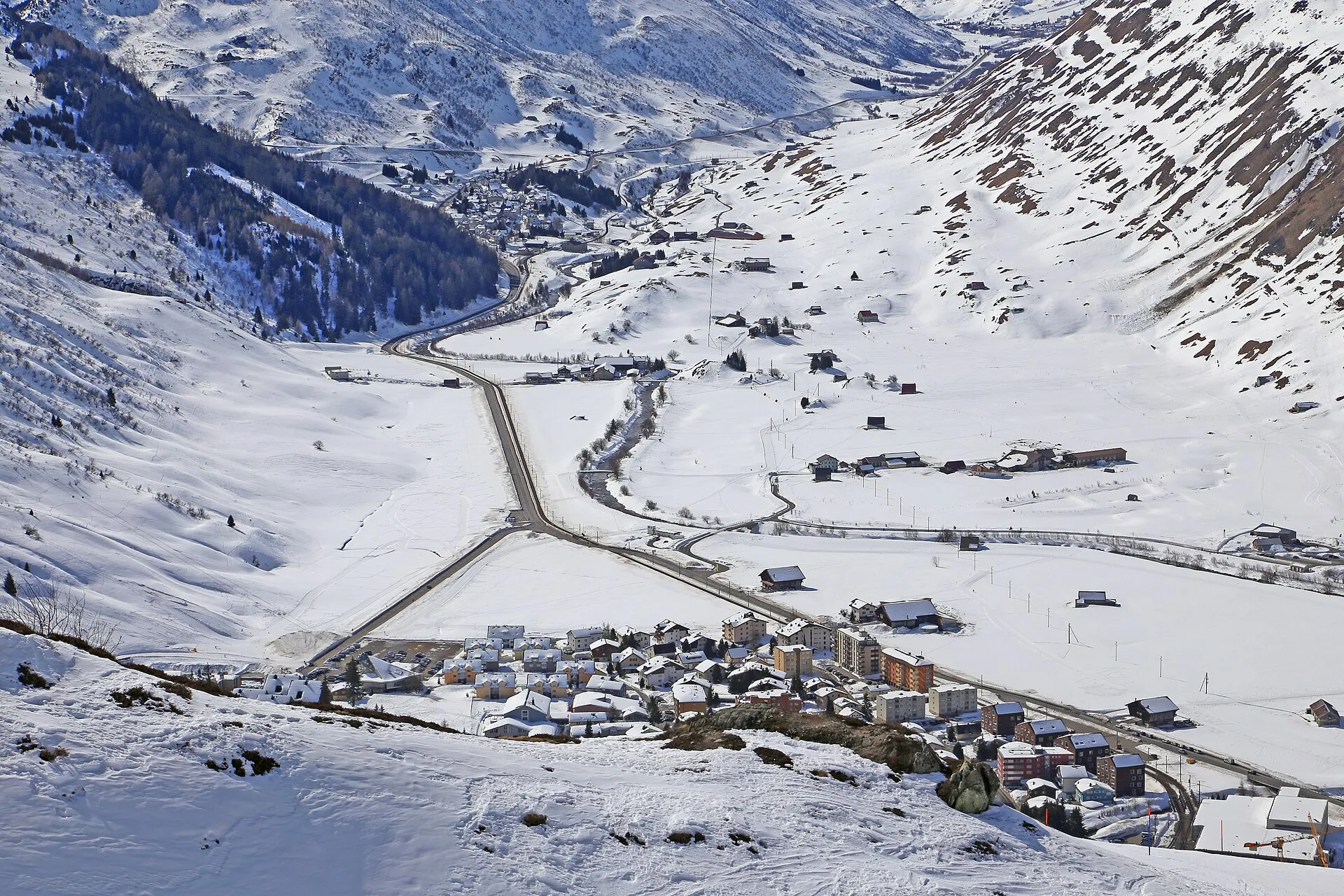 Blick von oben auf Andermatt und das verschneite Urserental mit der Strassengabelung Richtung Furka und Oberalp