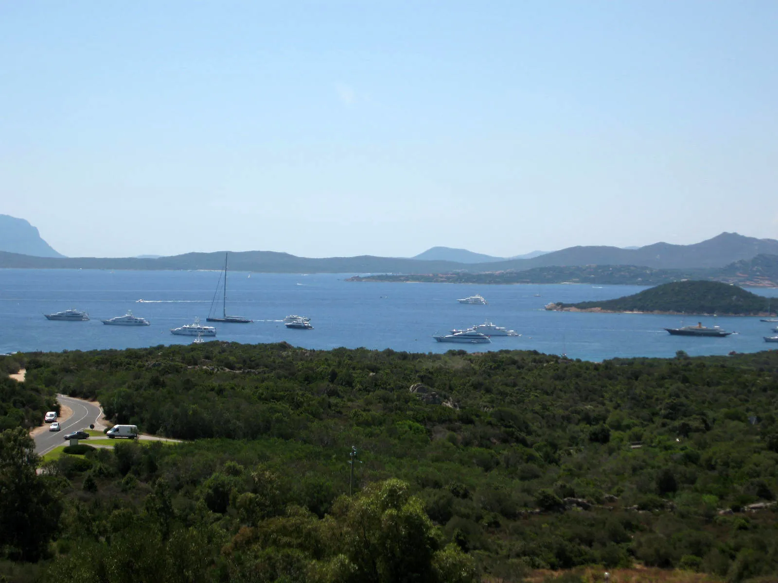 Blick über die Bucht von Cala di Volpe an der Costa Smeralda mit ankernden Jachten und bewaldeten Hügeln