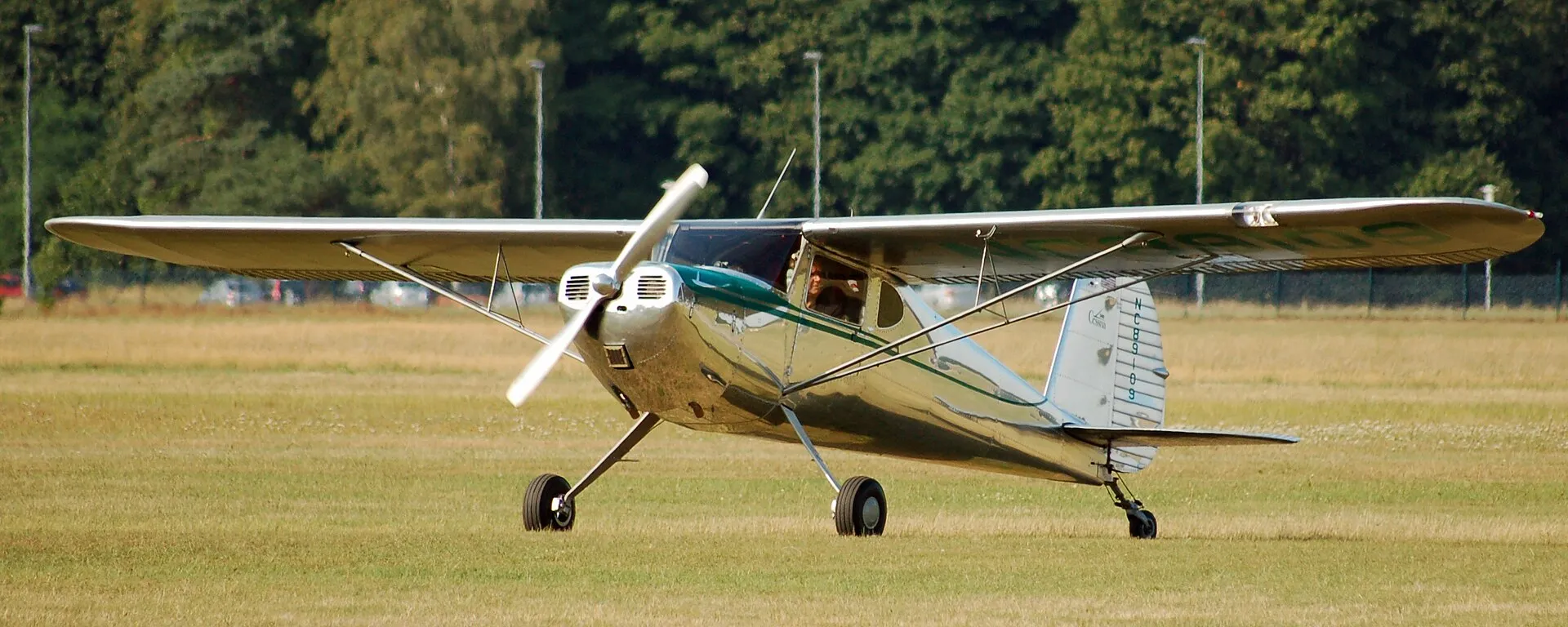 Silberne Cessna 140 mit abgestrebten Tragflächen auf einem Flugplatz