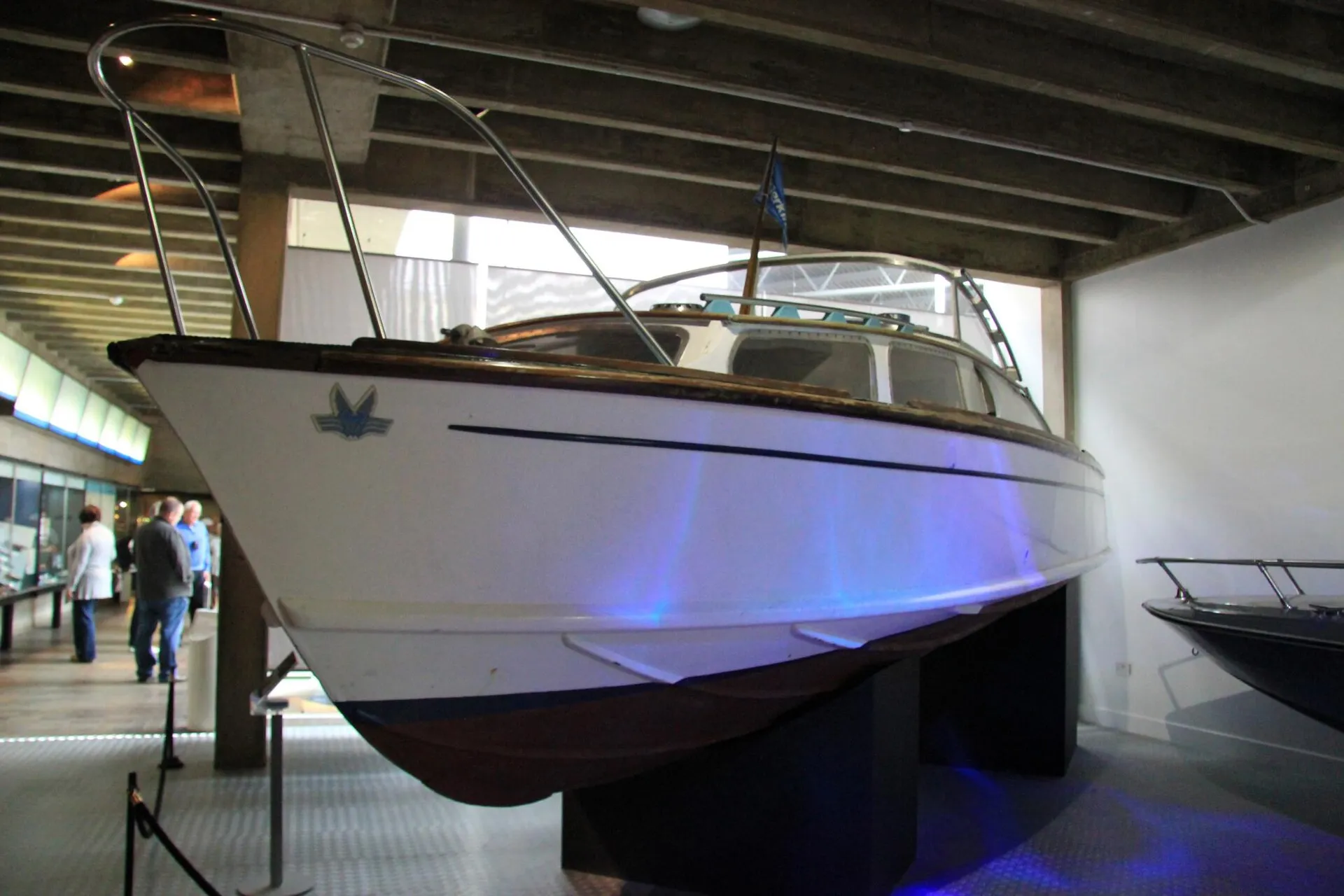 Weißes Fairey-Huntress-Motorboot mit Holzdeck und Reling auf einem Ausstellungssockel in einer Museumshalle