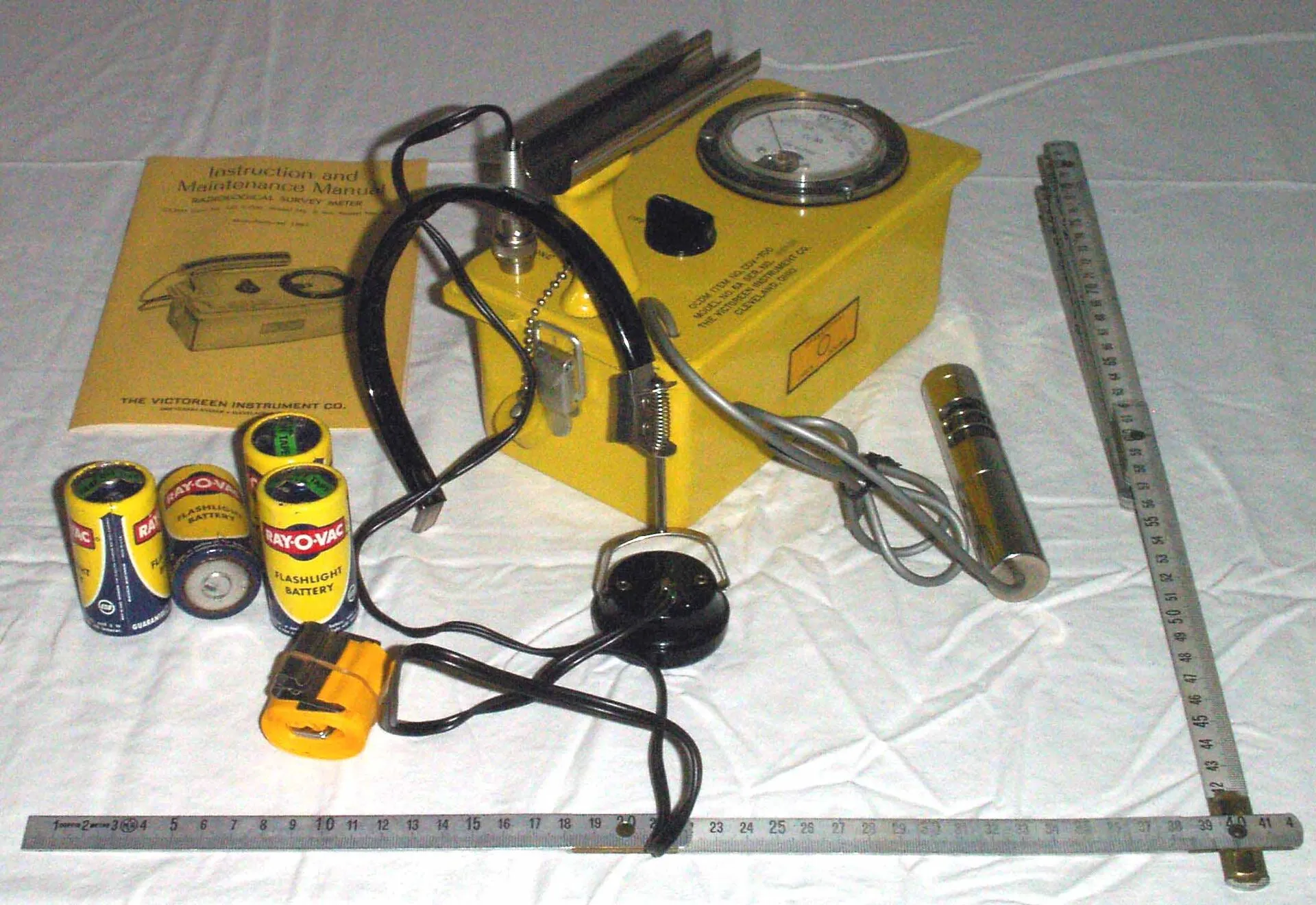 Gelber Geigerzähler Victoreen CD V-700 mit Sonde, Kopfhörer, Batterien und Handbuch auf weißem Tuch