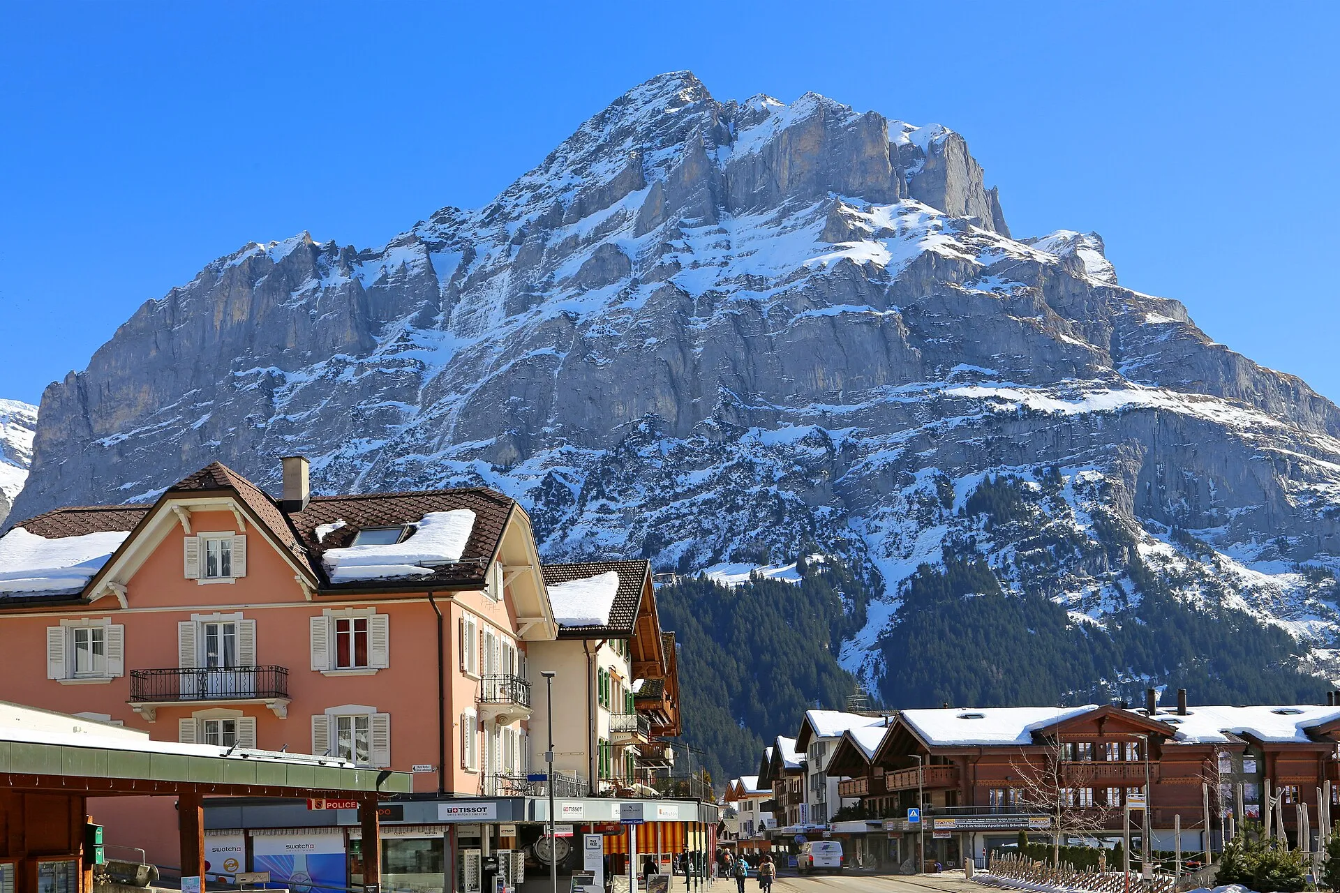 Verschneite Dorfstraße von Grindelwald mit Läden und Chalets vor der Felsflanke des Wetterhorns