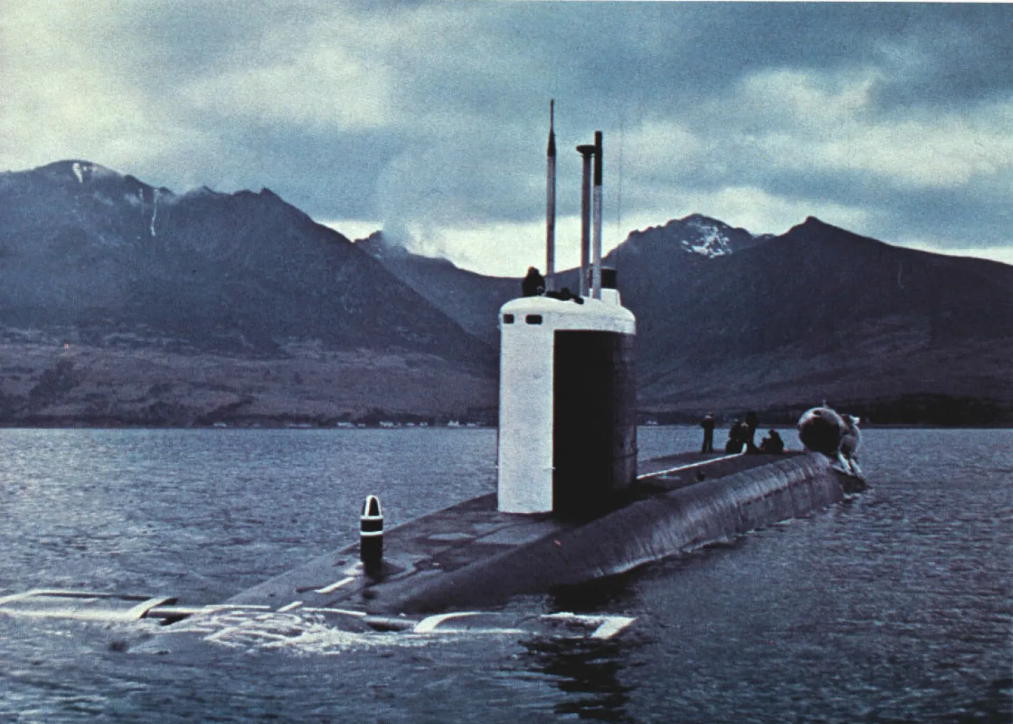 Aufgetauchtes Raketen-U-Boot mit weißem Turm auf einem schottischen Meeresarm, dahinter kahle Berge
