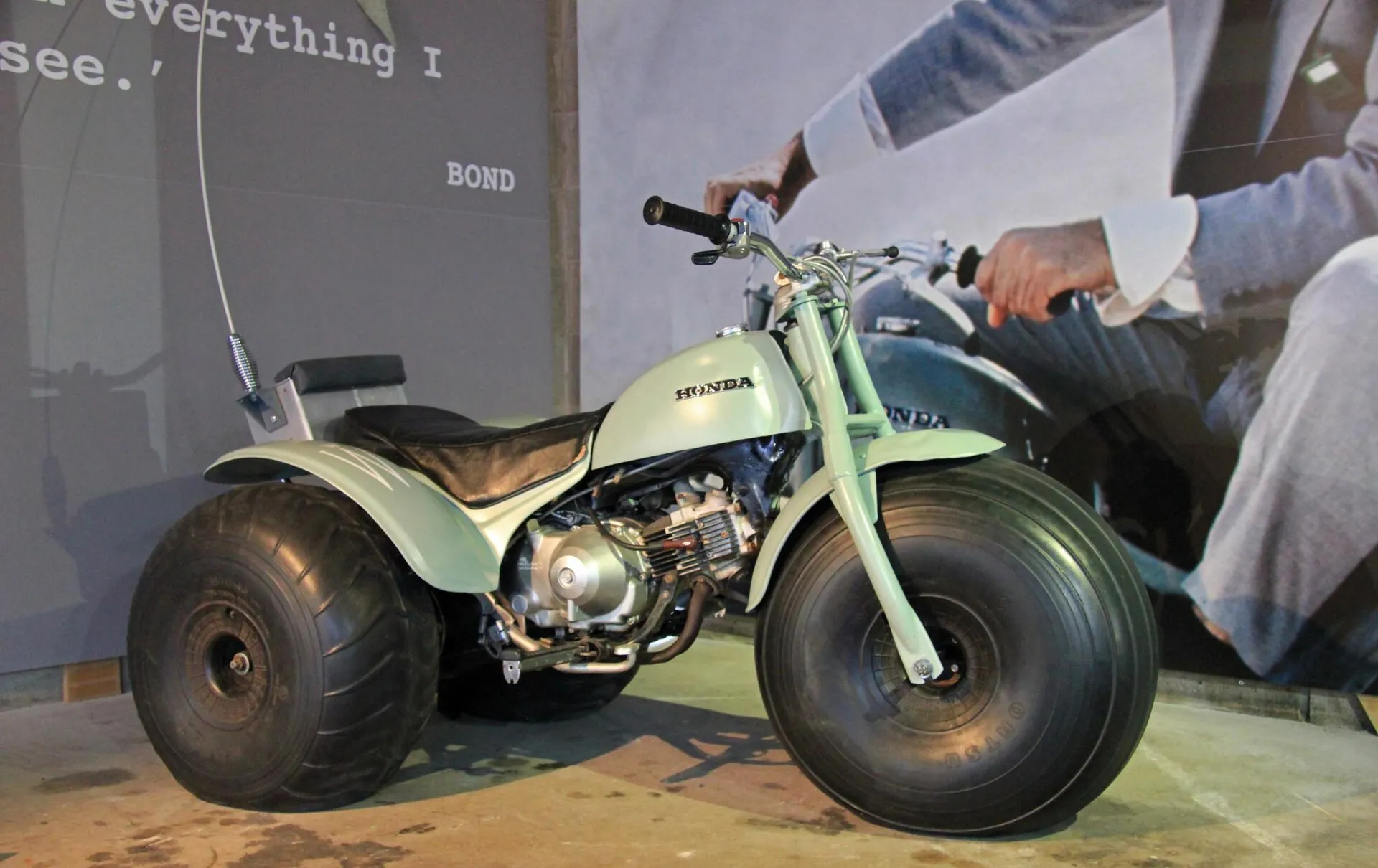 Hellgrünes Honda-Dreirad mit breiten Ballonreifen in der Ausstellung Bond in Motion.
