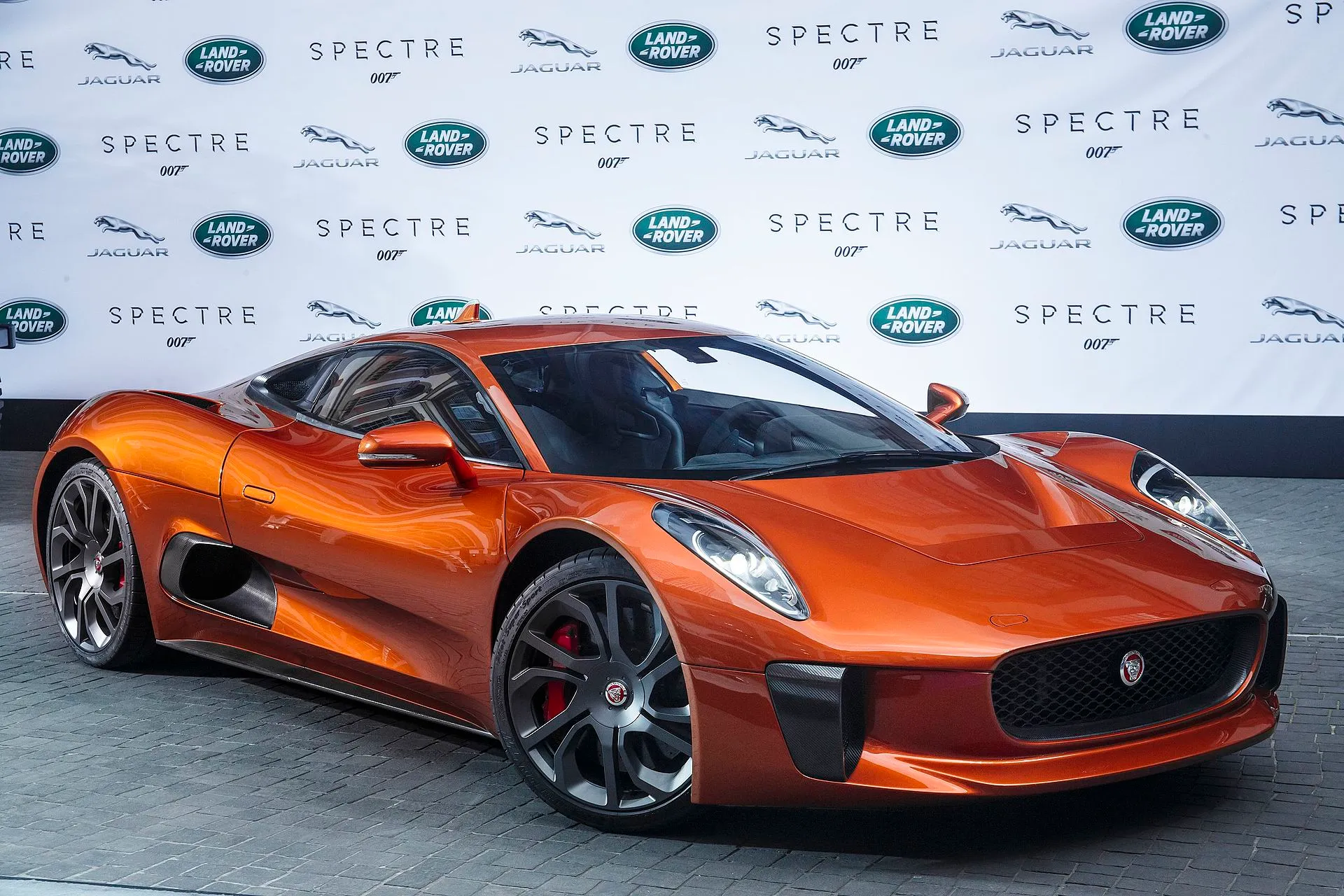 Kupferfarbener Jaguar C-X75 vor einer Spectre-Präsentationswand