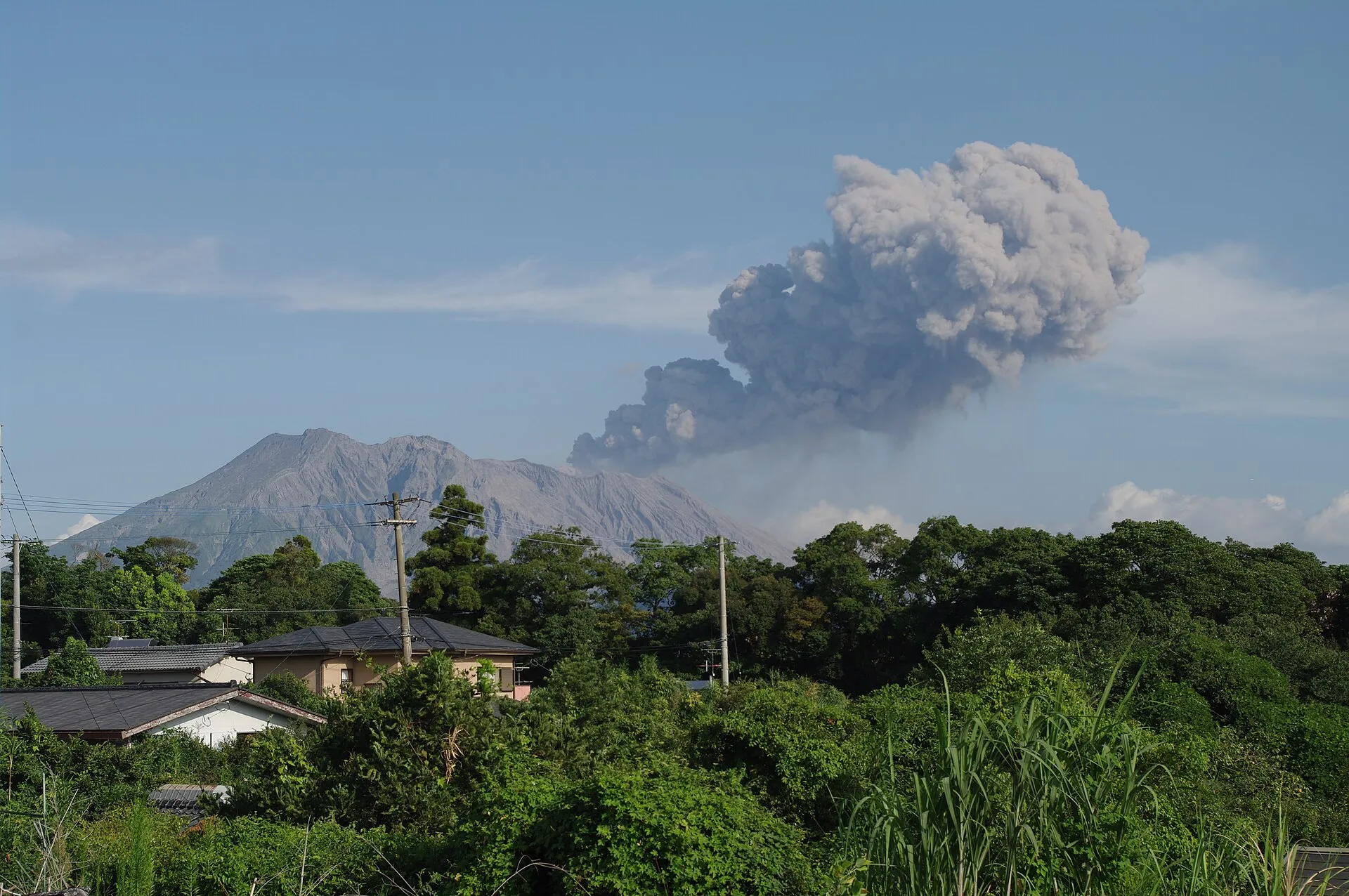 Der Vulkan Sakurajima bei Kagoshima stößt eine Aschewolke aus, im Vordergrund Wohnhäuser