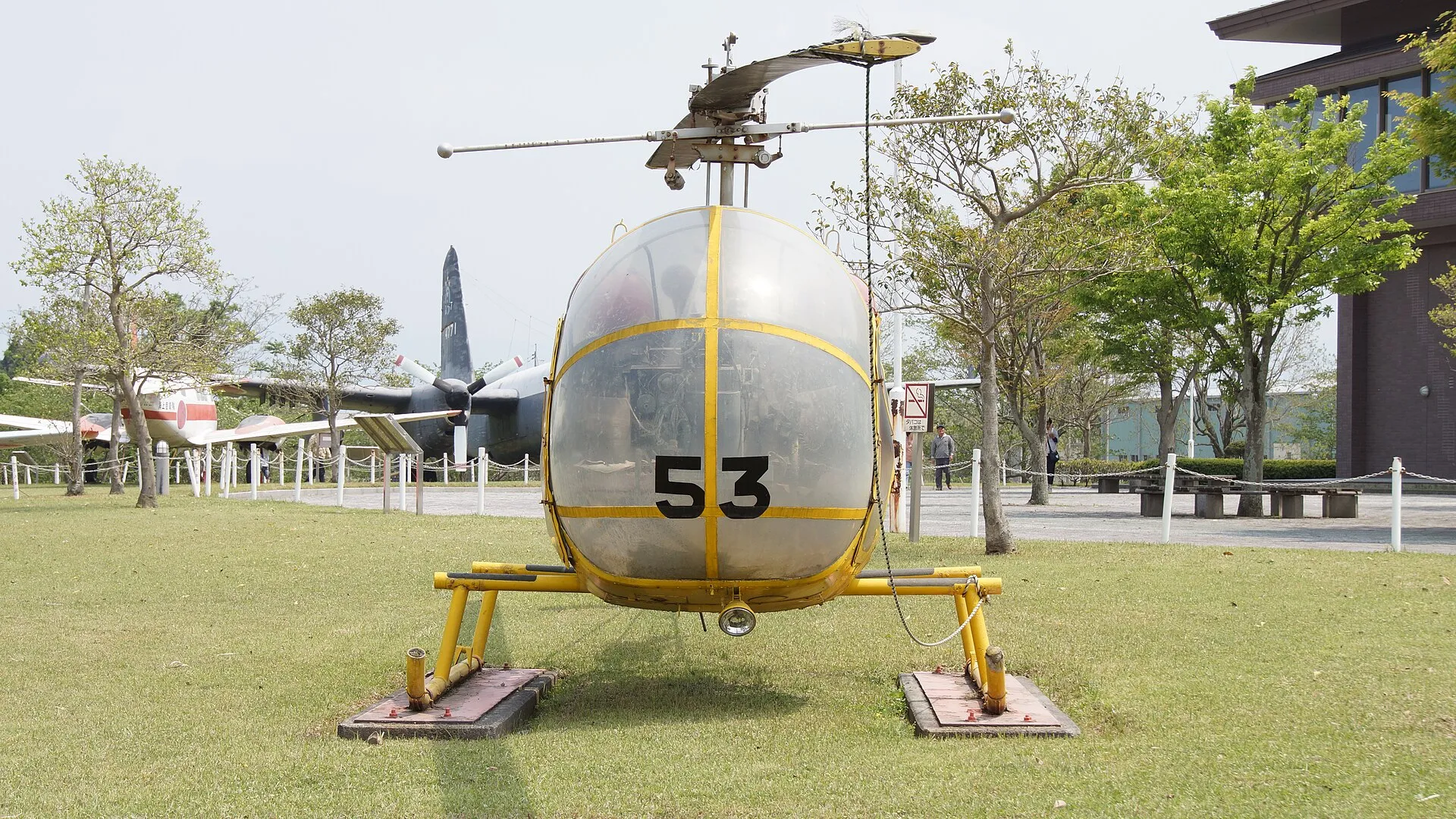 Kawasaki-Bell 47G-2A mit Glaskanzel und gelbem Rahmen frontal auf einer Wiese