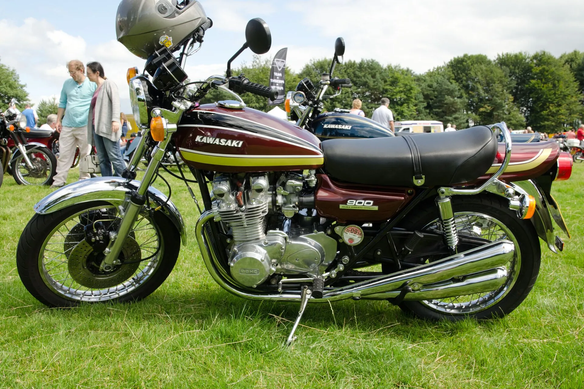 Dunkelrote Kawasaki Z900 mit vier Auspuffrohren und der Aufschrift „900“ am Seitendeckel, seitlich auf einer Wiese