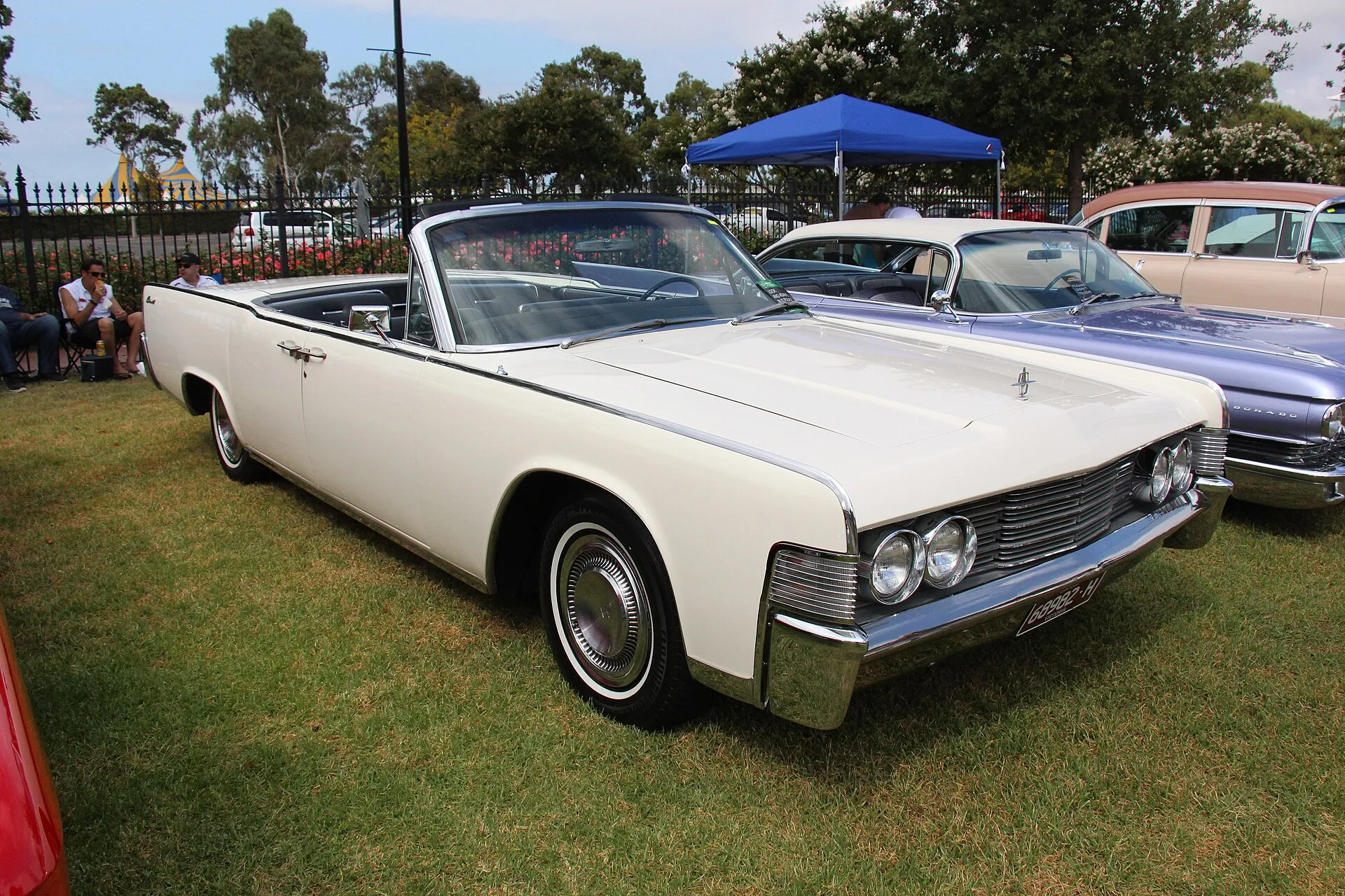 Weißes viertüriges Lincoln Continental Cabriolet von 1965 mit offenem Verdeck auf einer Wiese