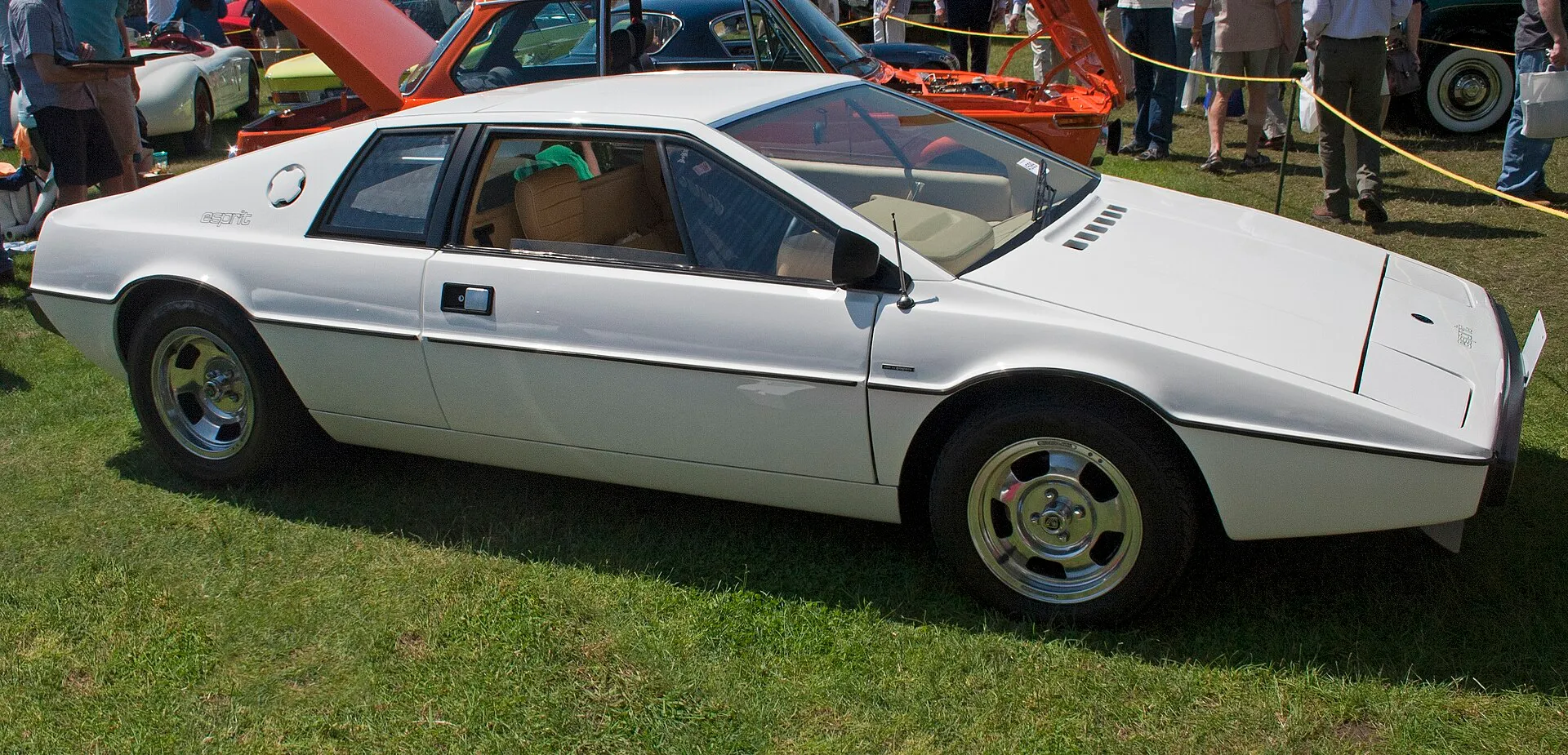 Weißer Lotus Esprit S1 mit Keilform in Seitenansicht auf einer Wiese bei einem Oldtimertreffen