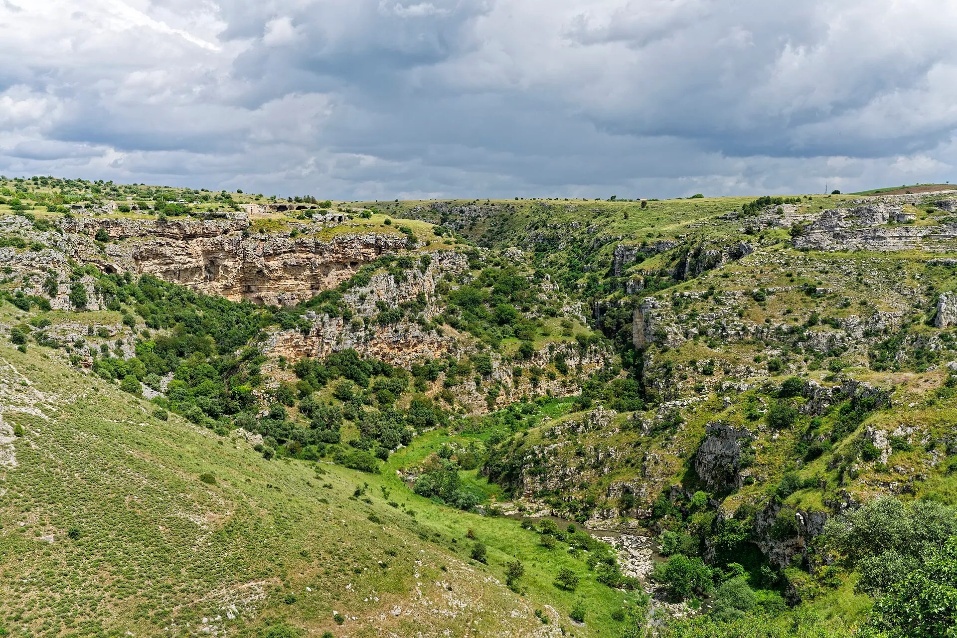 Felsige Schlucht der Gravina bei Matera unter dramatischen Wolken