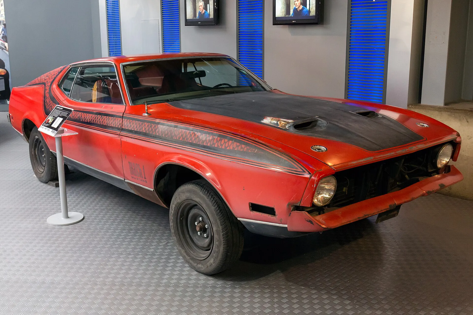 Roter Ford Mustang Mach 1 mit schwarzer Motorhaube in der Ausstellung Bond in Motion.