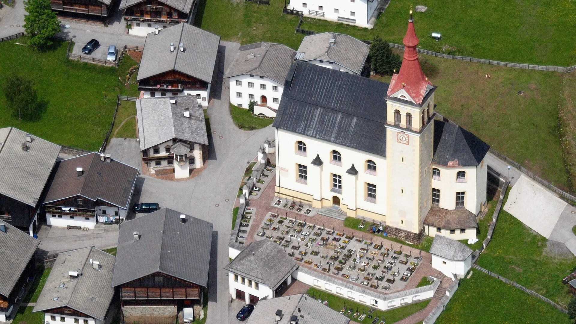 Luftbild der Kirche und Häuser von Obertilliach
