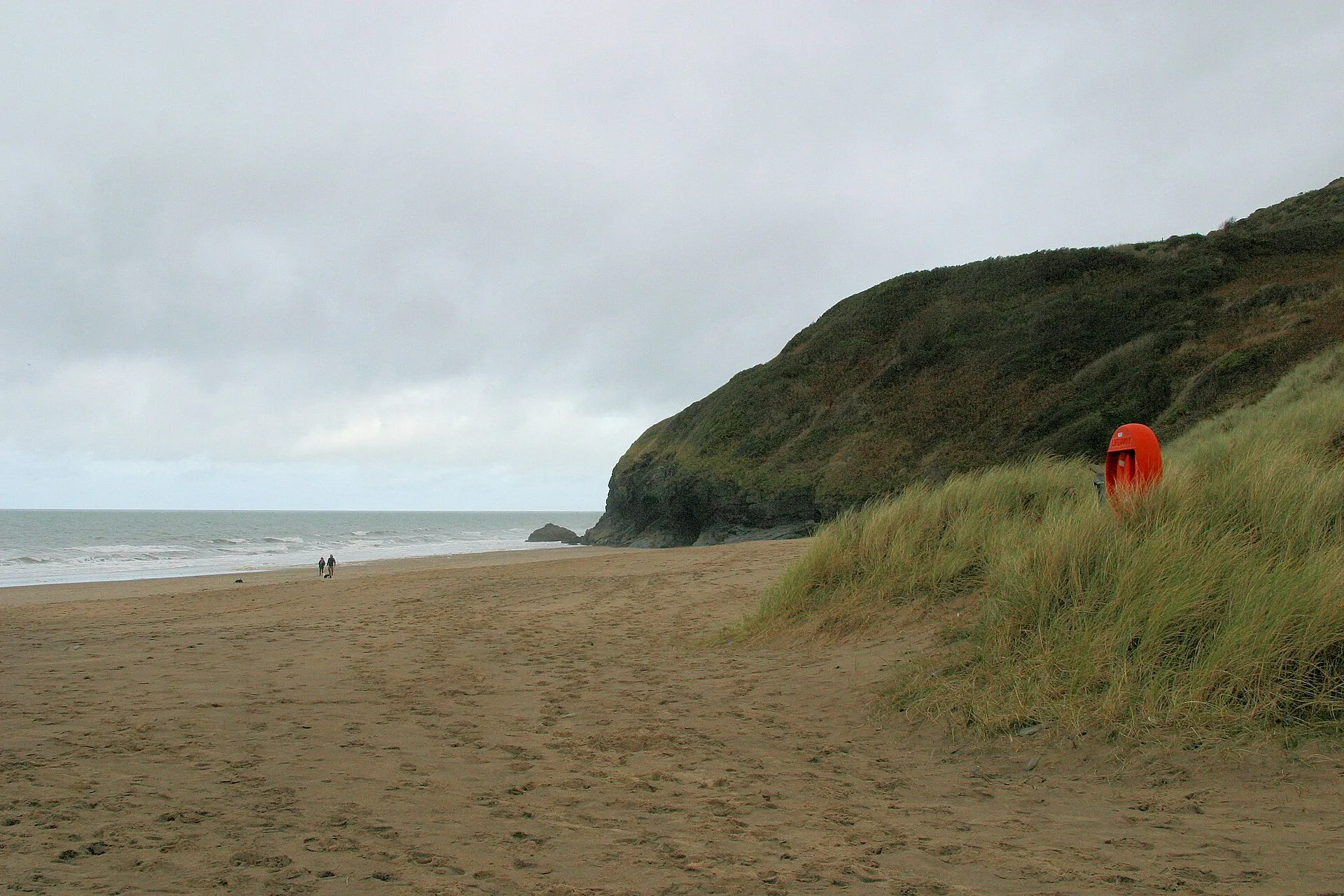 Abgelegener Sandstrand von Penbryn unter bewaldeten Klippen