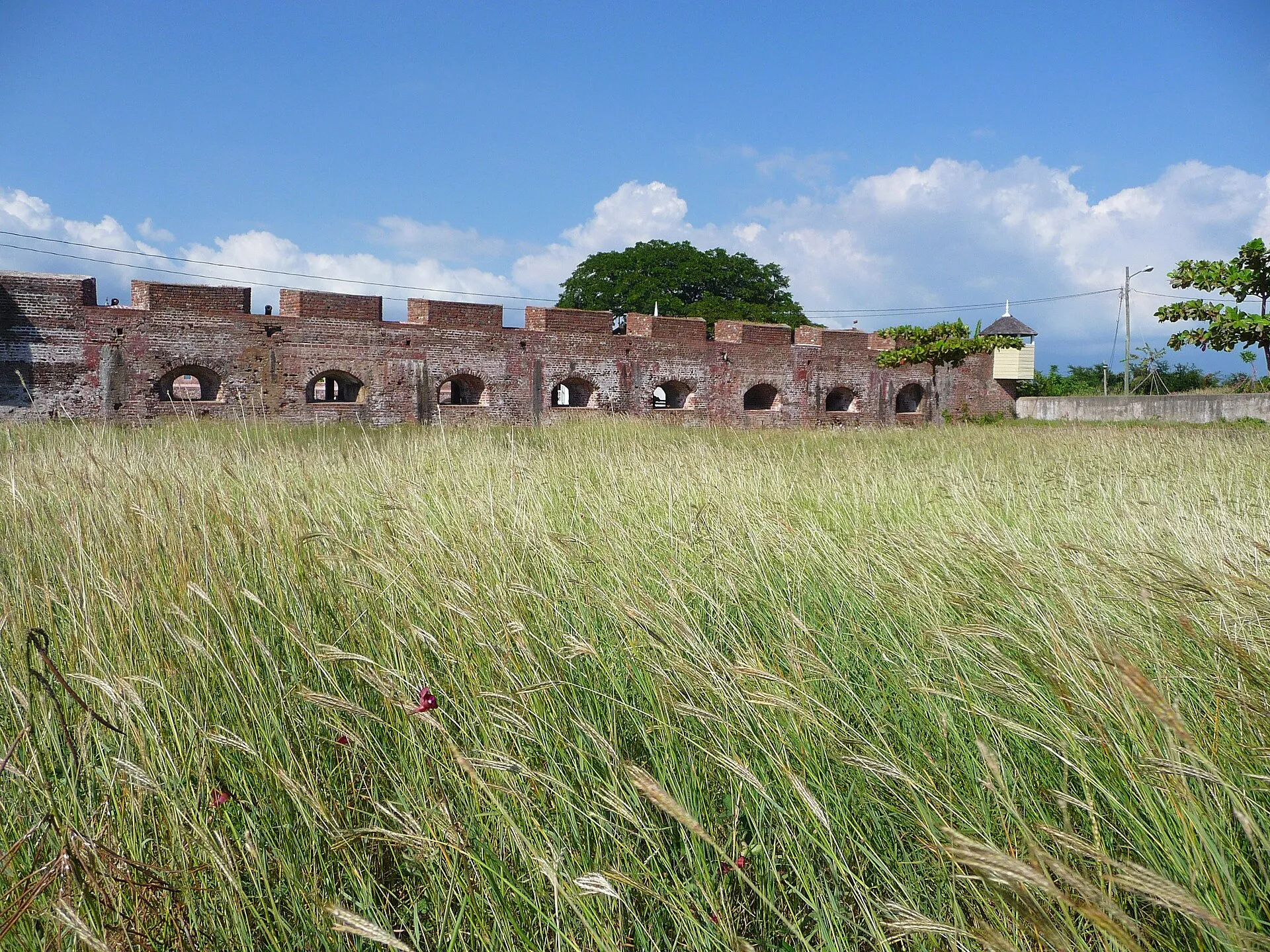 Die roten Backsteinmauern von Fort Charles in Port Royal hinter hohem, windbewegtem Gras