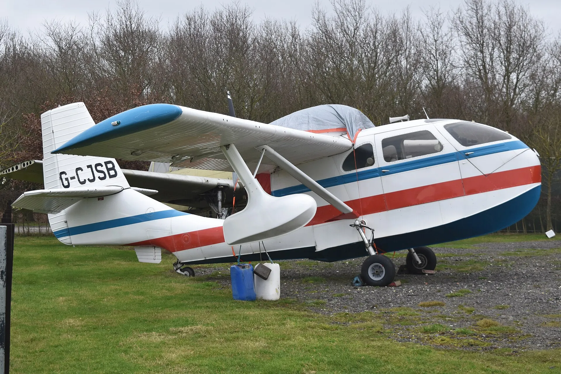 Weiß-rot-blaues Amphibienflugzeug Republic RC-3 Seabee mit dem Kennzeichen G-CJSB auf einer Wiese, die Druckschraube sitzt hinter der Kabine über dem Rumpf