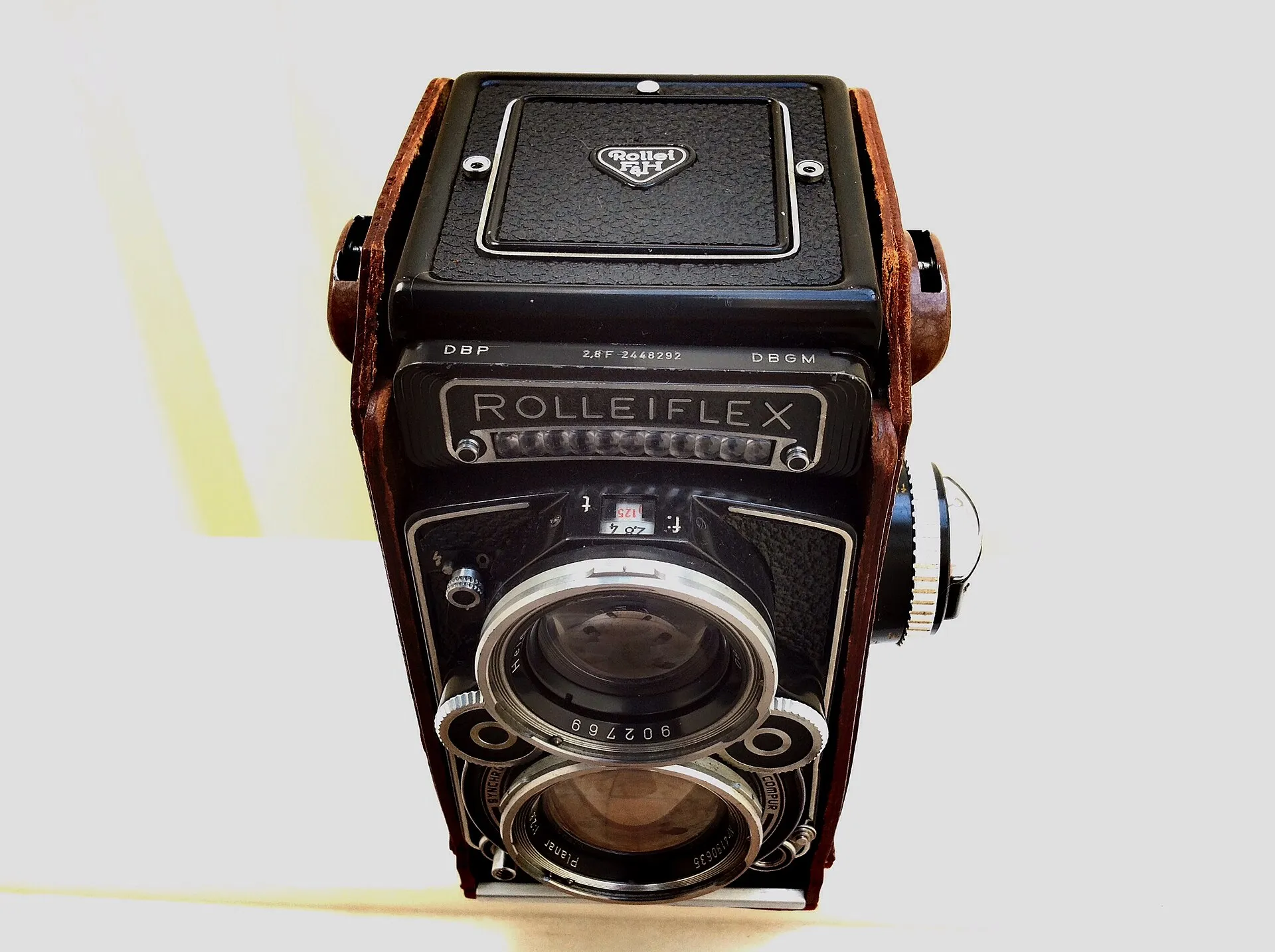 Zweiäugige Rolleiflex 2,8F von 1964 mit Planar-Objektiv und brauner Ledertasche vor hellem Hintergrund