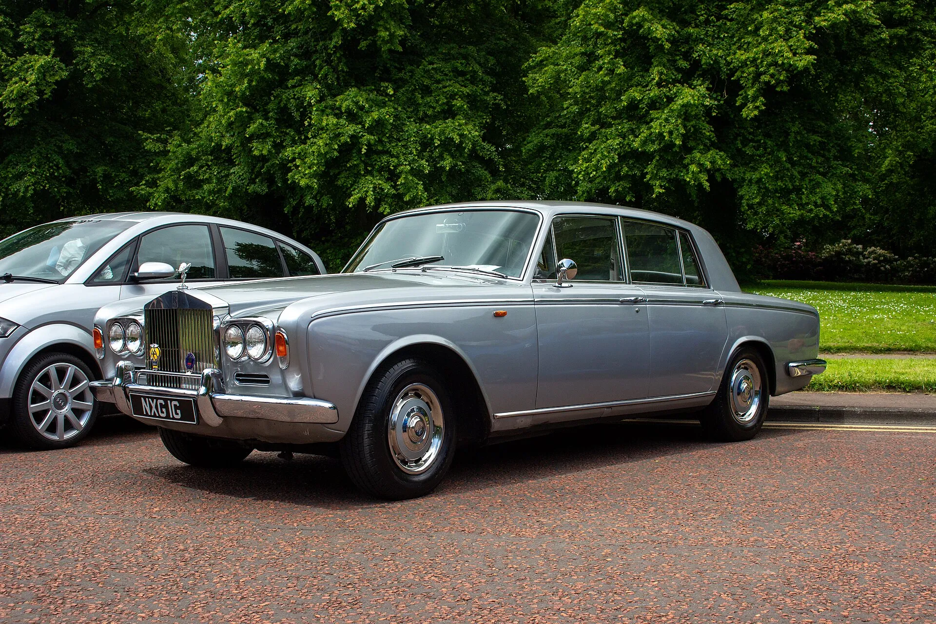 Silbergraue Rolls-Royce-Silver-Shadow-Limousine von 1969 mit Doppelscheinwerfern, am Straßenrand vor Bäumen geparkt