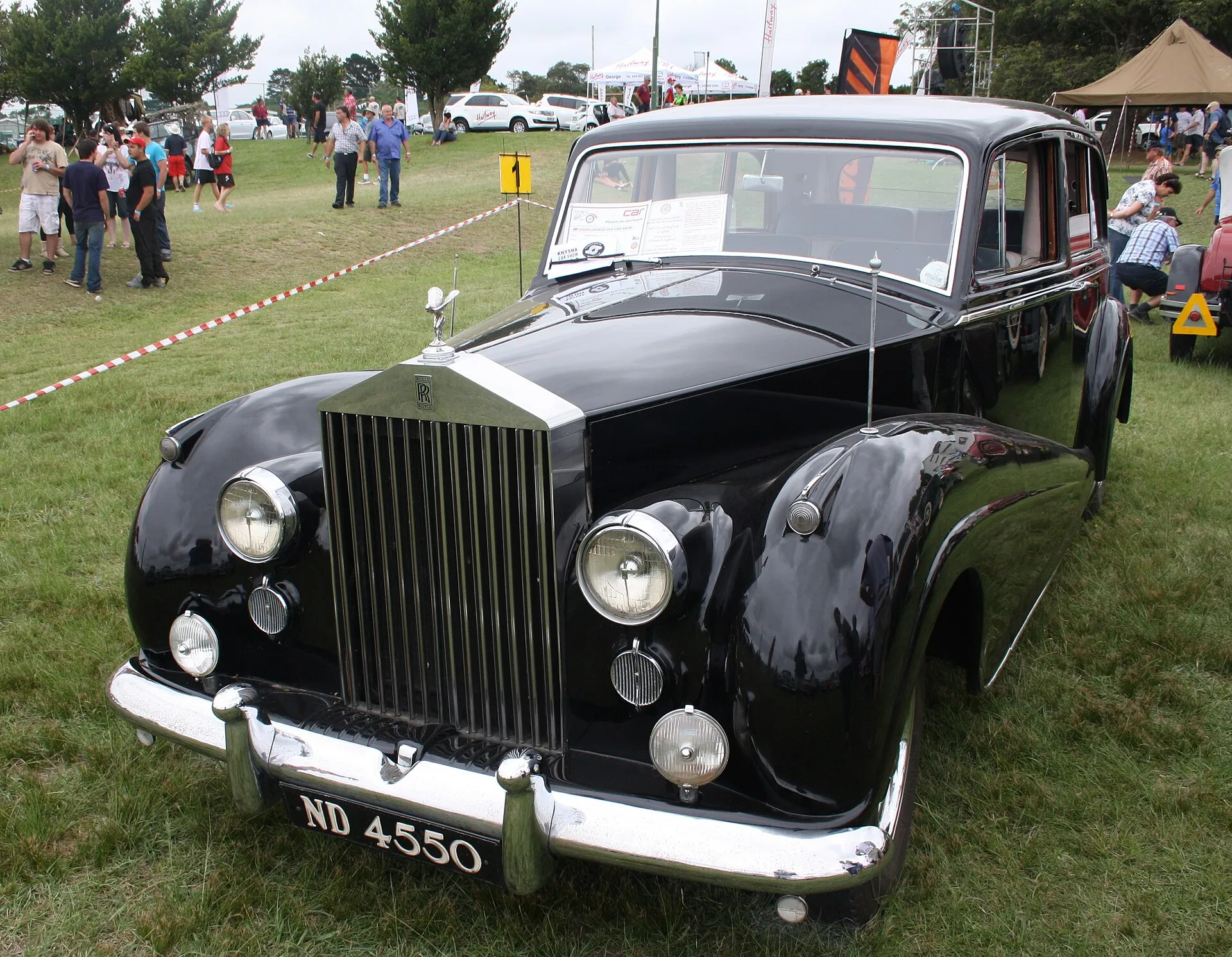 Schwarze Rolls-Royce Silver Wraith Limousine von 1958 mit Kühlerfigur und Zusatzscheinwerfern auf einer Wiese bei einer Oldtimerschau