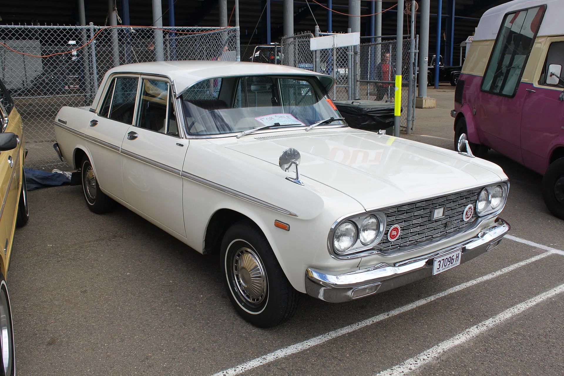 Weiße Toyota-Crown-Limousine der zweiten Generation mit Doppelscheinwerfern auf einem Parkplatz