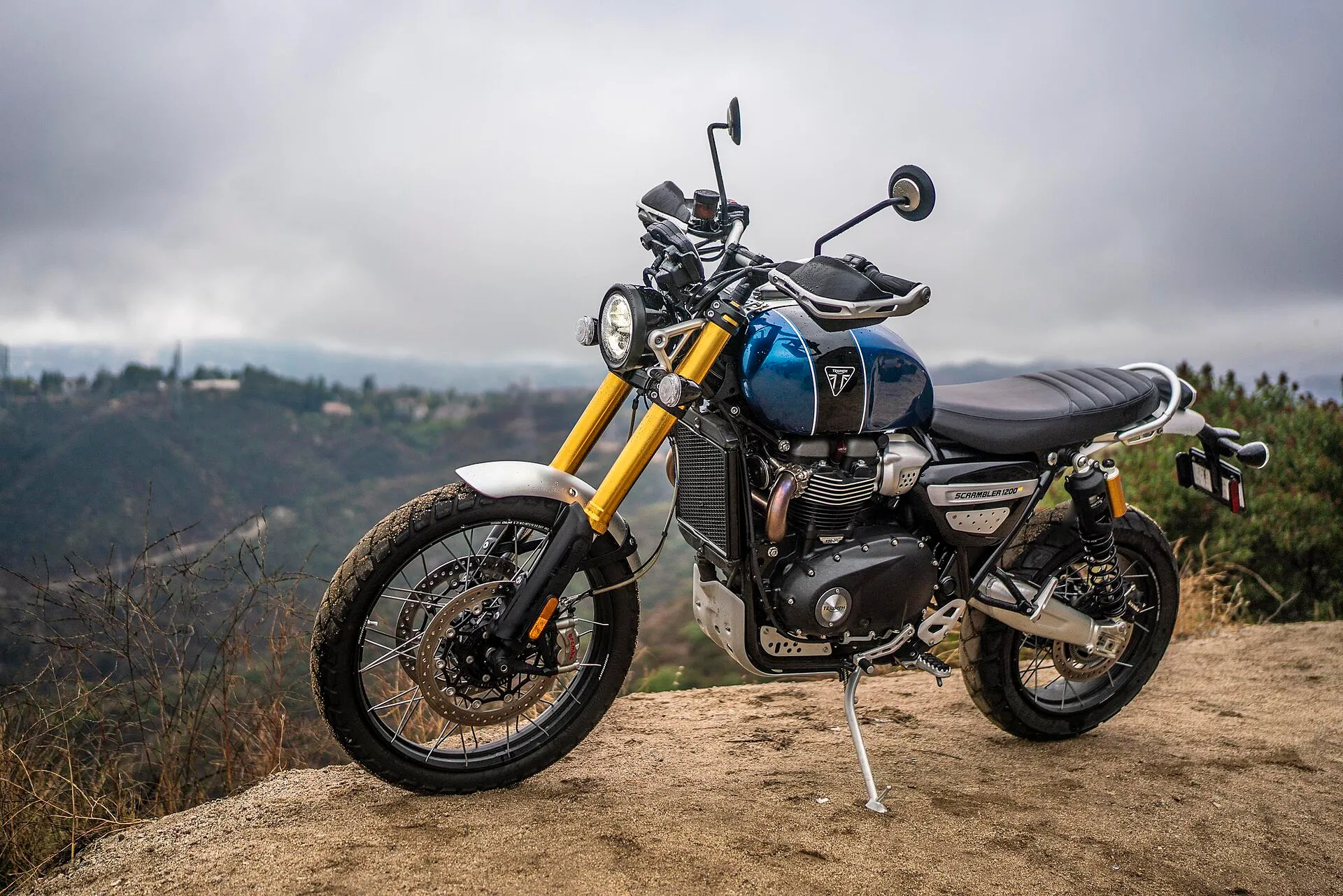 Blaue Triumph Scrambler 1200 XE in einer Berglandschaft