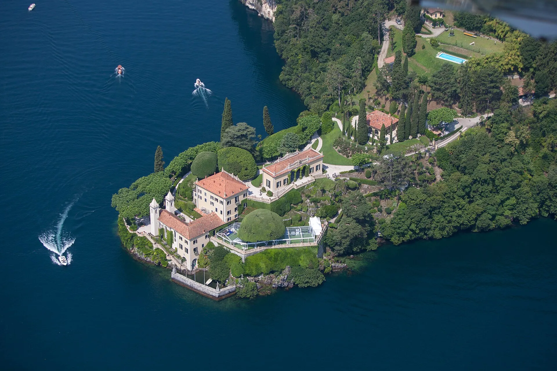 Luftaufnahme der Villa del Balbianello auf einer bewaldeten Landzunge im Comer See