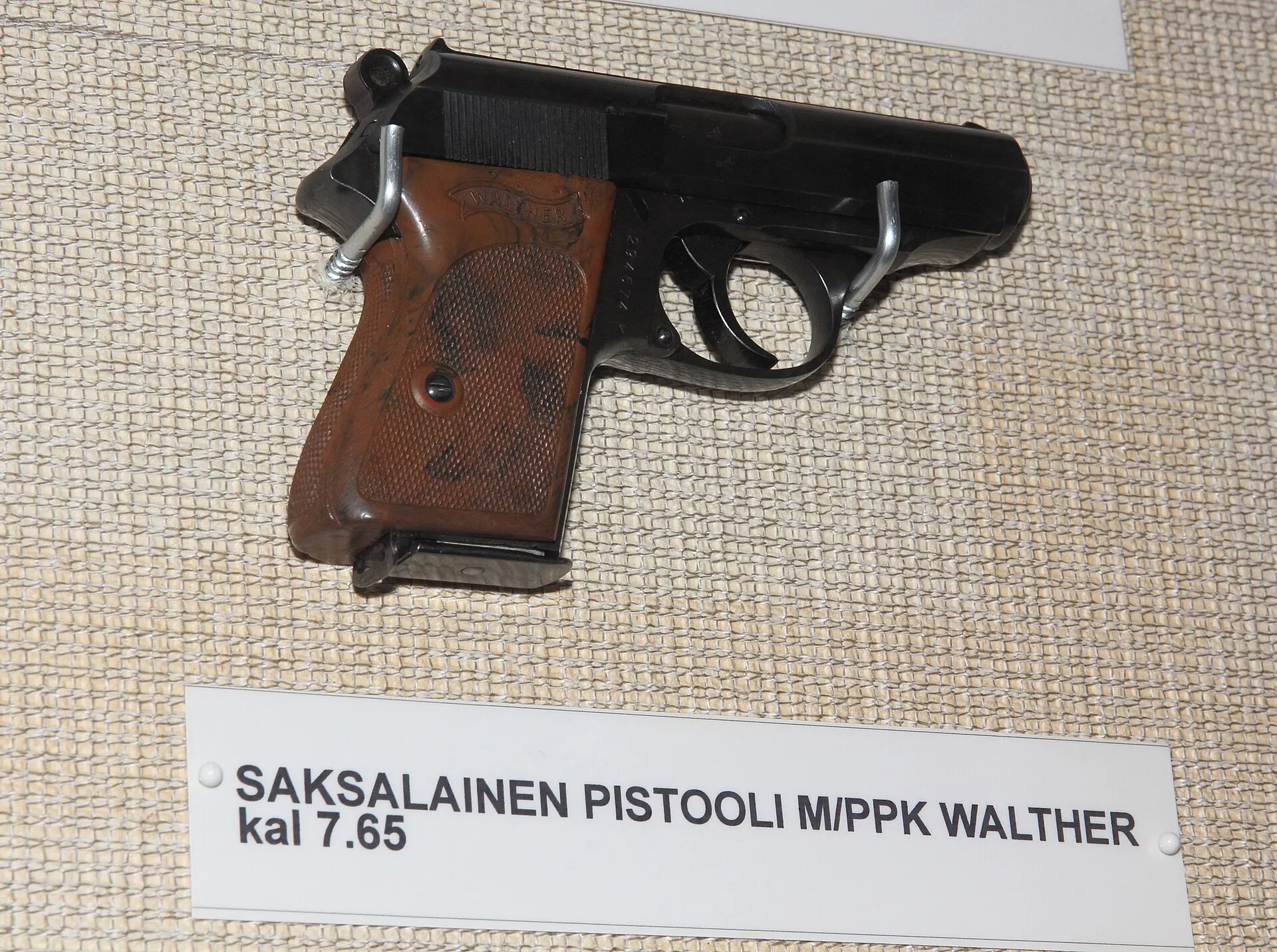 Walther PPK mit braunen Griffschalen und einer Museumsbeschriftung zum Kaliber 7,65 mm.