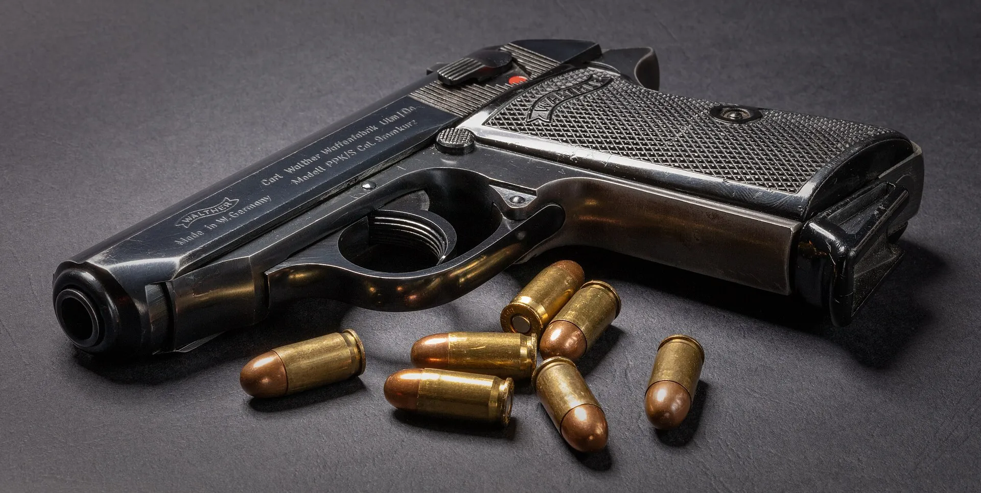 Walther PPK mit Patronen auf dunklem Untergrund